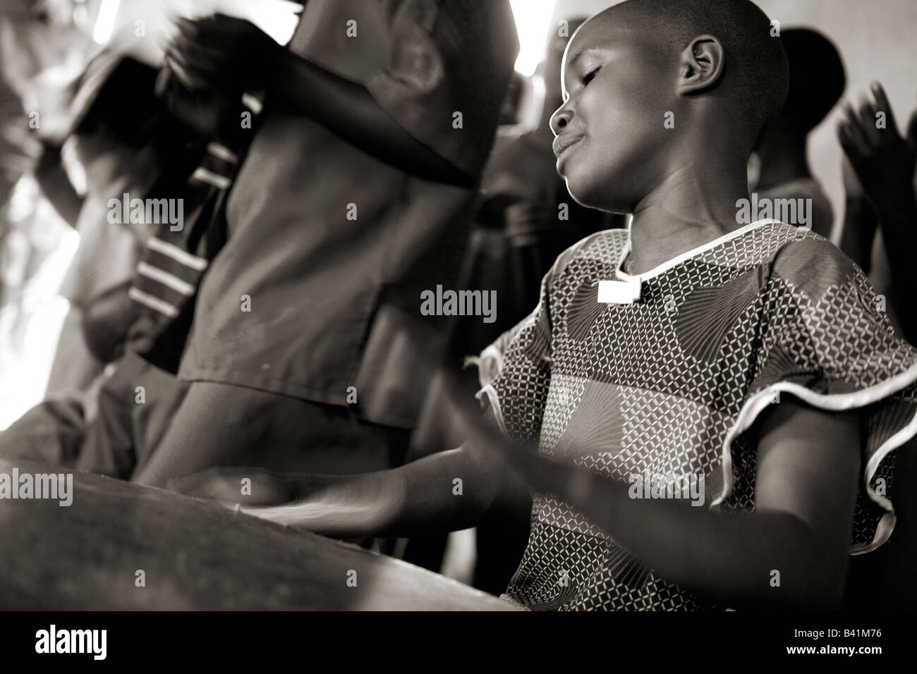 Ein junges Mädchen spielt die Trommel, wie sie den Kinderchor in Gisenyi, Ruanda führt. Stockfoto