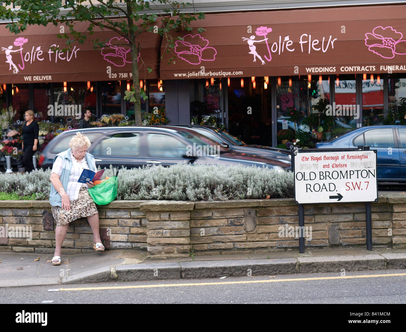 Ältere Dame, ein Buch zu lesen, während des Wartens South Kensington London UK Stockfoto