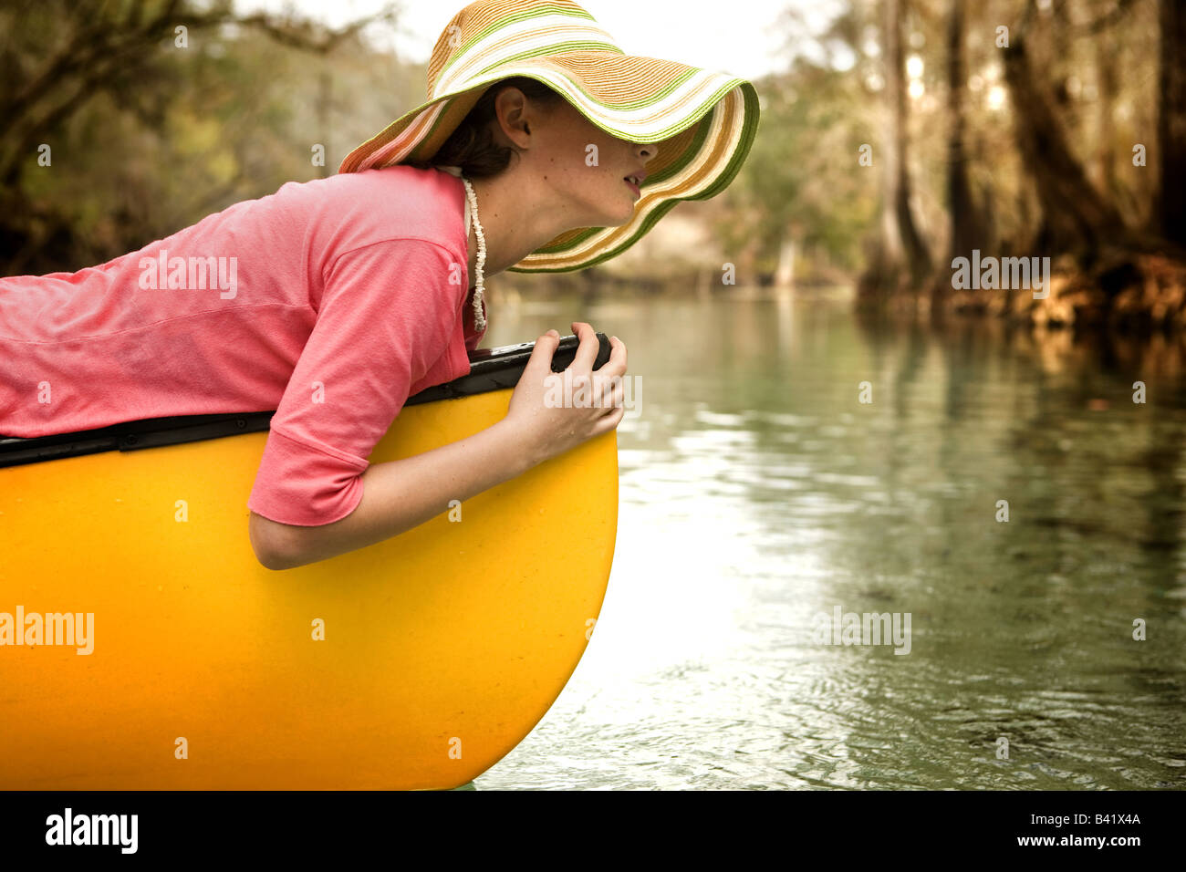 Ein junges Mädchen entspannt auf ihrem Kanu im klaren Wasser, Zypressen gesäumten Fluss von einem frischen Quellwasser in High Springs, Florida. Stockfoto