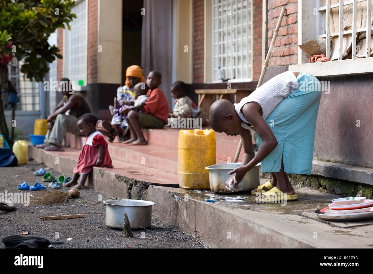 Ein junges Mädchen ruandischen wäscht die Gerichte außerhalb der Duplex, in den sie lebt. Stockfoto
