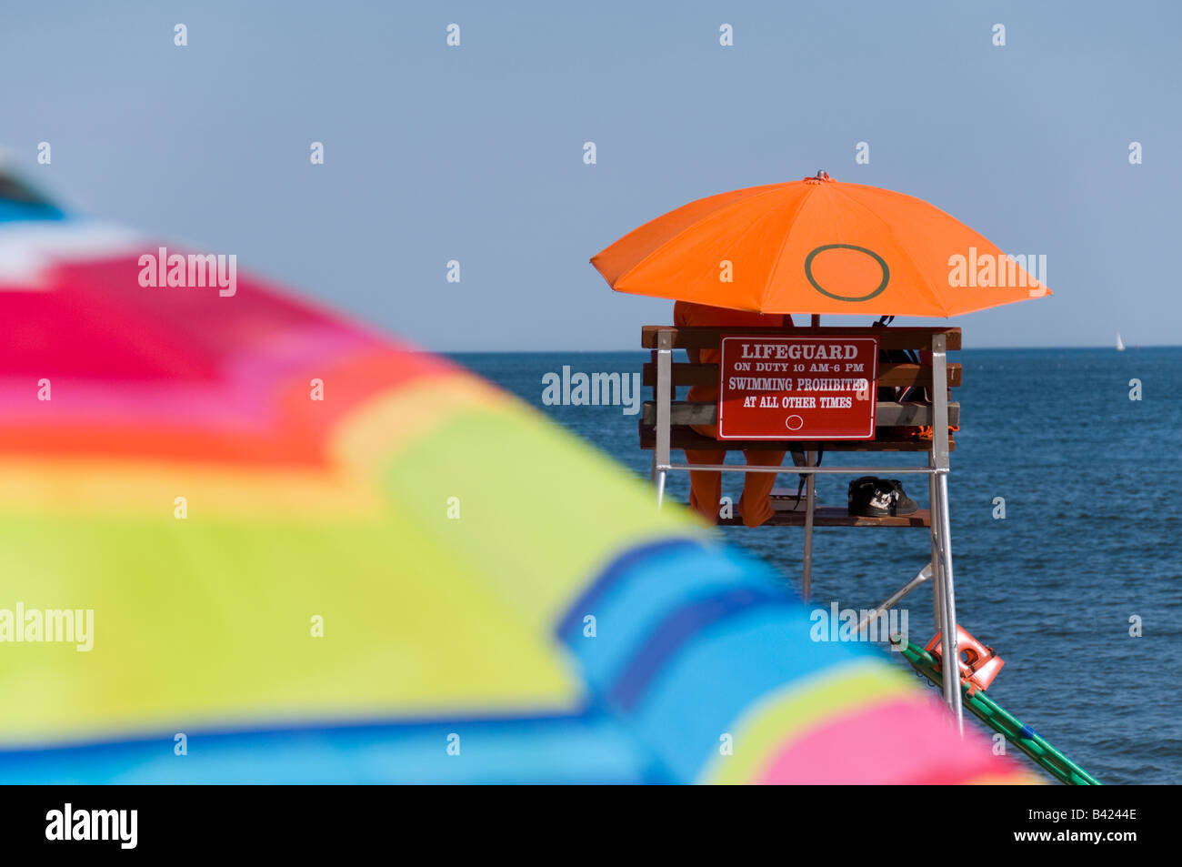 Ein Rettungsschwimmer von der Sommersonne unter Regenschirm orange bergende. Stockfoto