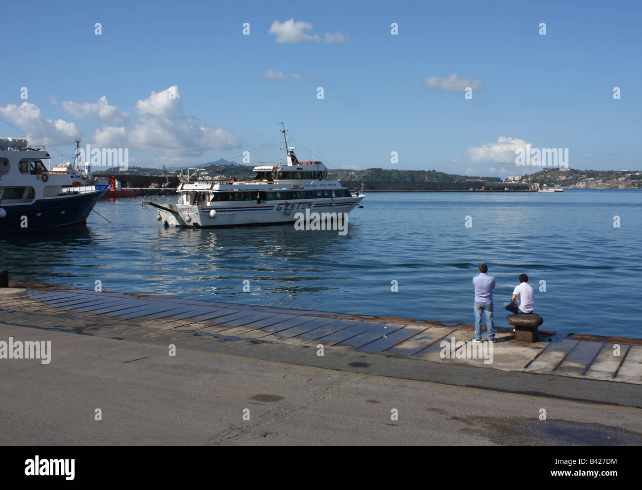 Zwei Männer beobachten ein Boot am Hafen von Pozzuoli in Süditalien zu verlassen Stockfoto