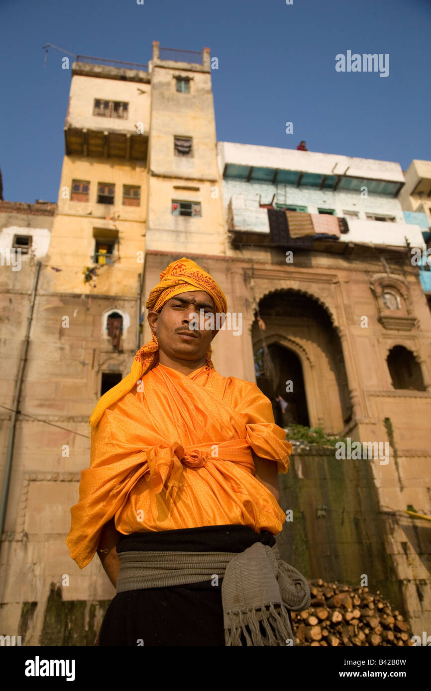 Ein junger Sadhu steht vor einer der am Flussufer Tempel in der Stadt von Varanasi, Indien. Er trägt Orange. Stockfoto