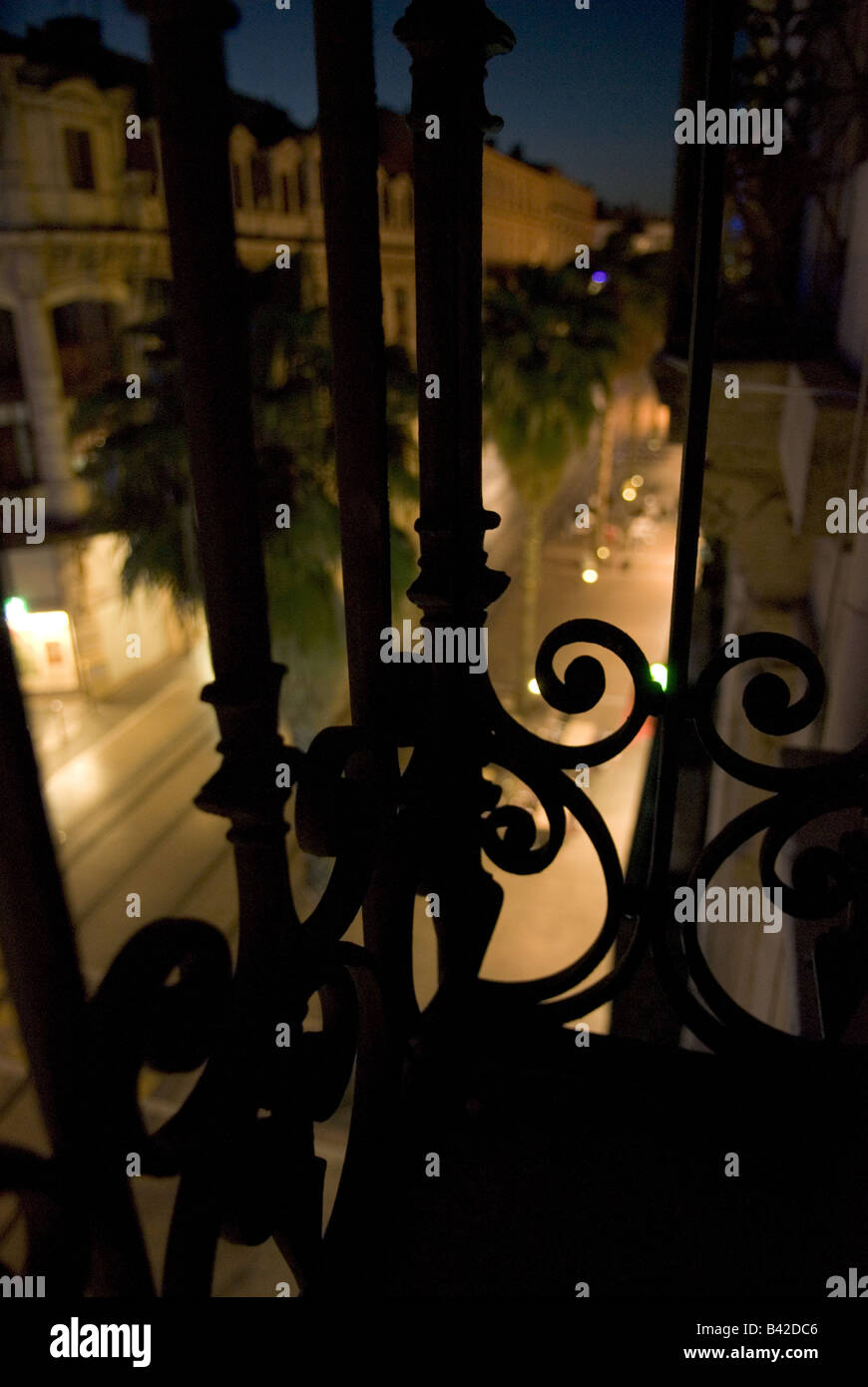 malerische Aussicht durch einen schmiedeeisernen Balkon eines Montpelliers Palm gesäumten Hauptstraßen in der Nacht Stockfoto