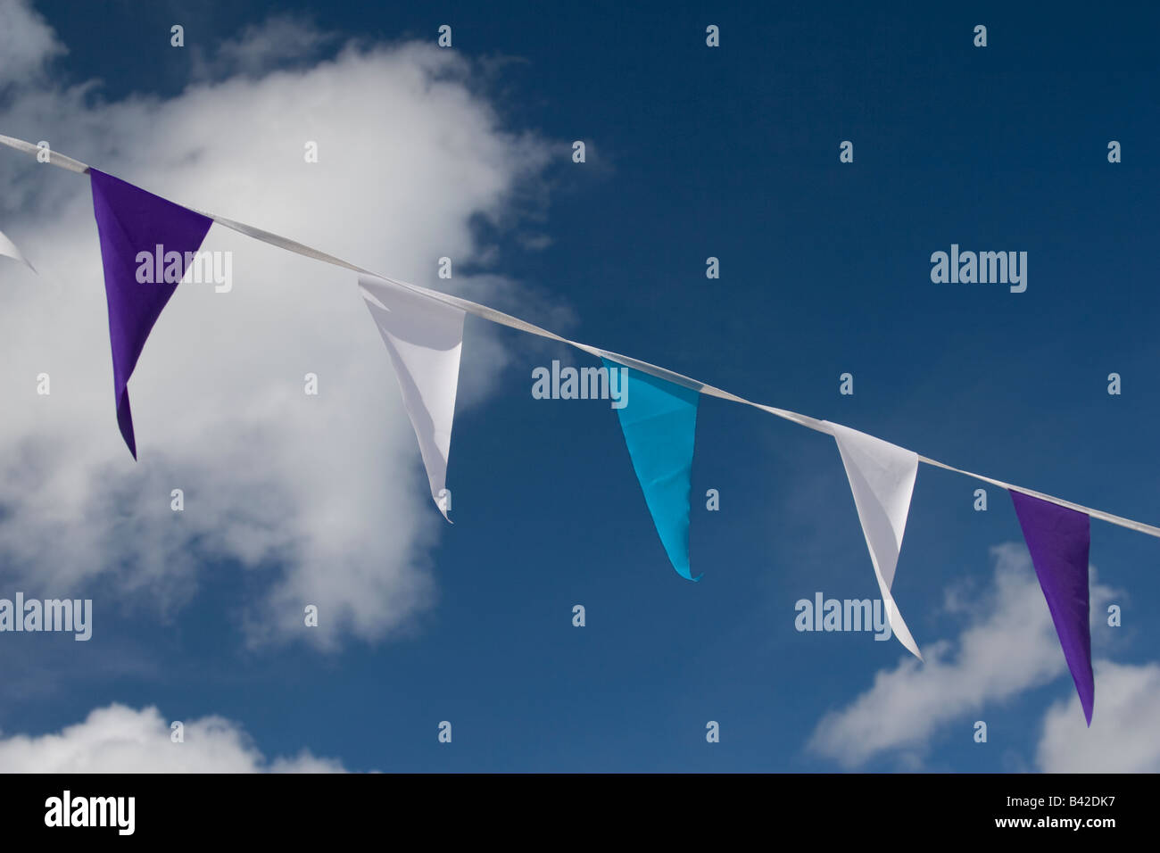 Party Girlanden Fahnen in verschiedenen Farben mit Wolken und blauer Himmel im Hintergrund. Stockfoto