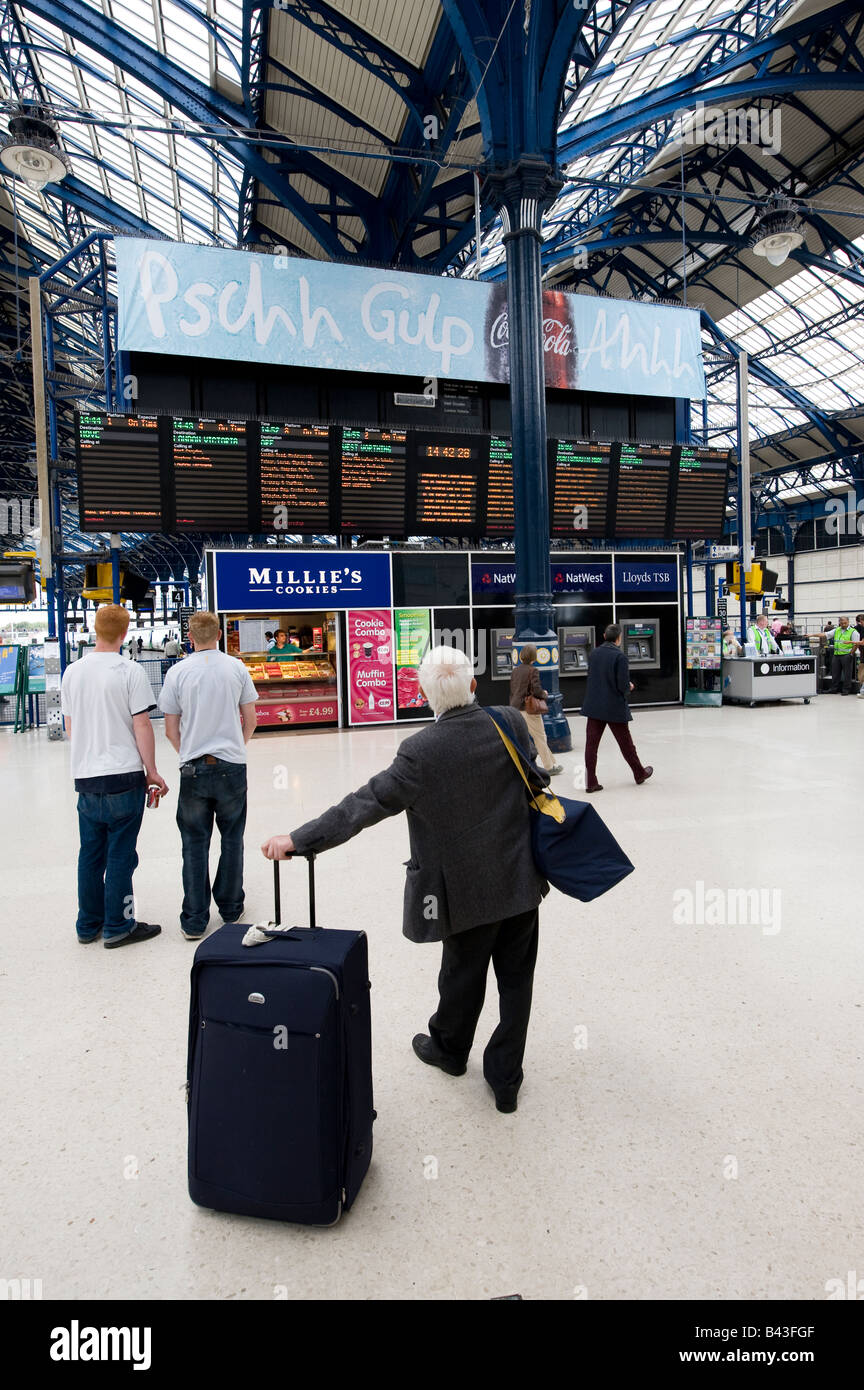 Leute warten vor den Zeitplan Informationstafeln im Bereich Halle des Brighton Station East Sussex uk Stockfoto