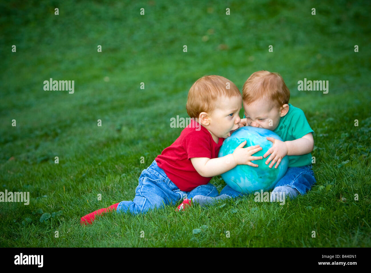 Junge rothaarige Baby jungen draußen auf dem Rasen spielen mit ball Stockfoto