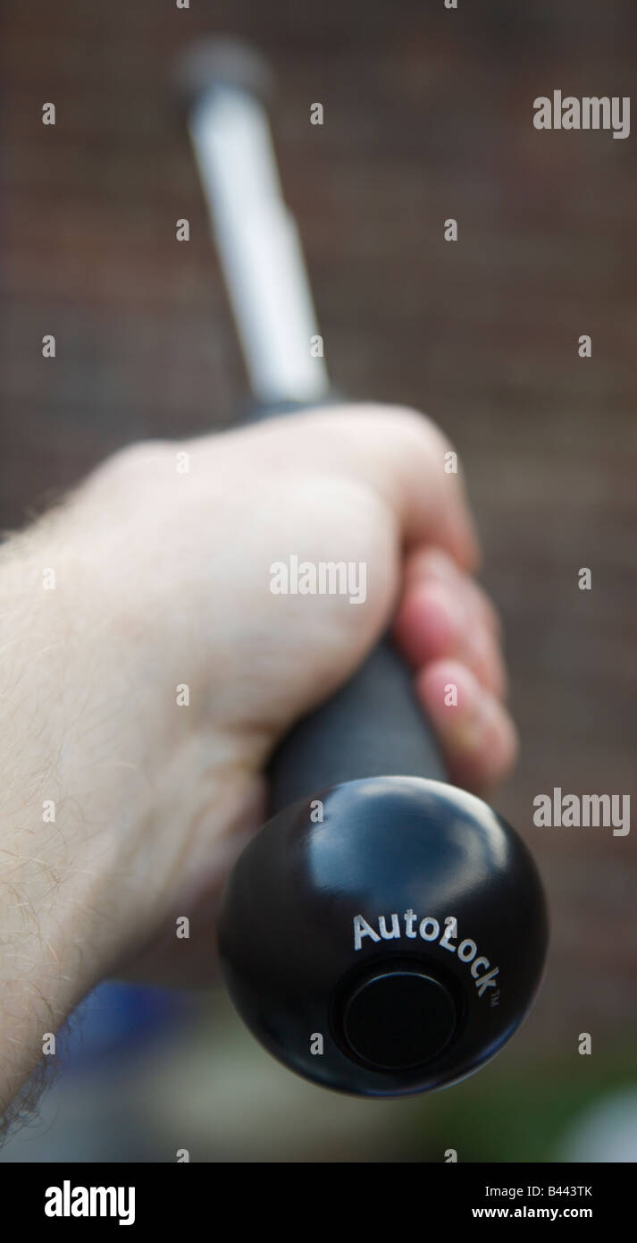 Ein britischer Polizist erstreckt sich Taktstock autolock Stockfoto