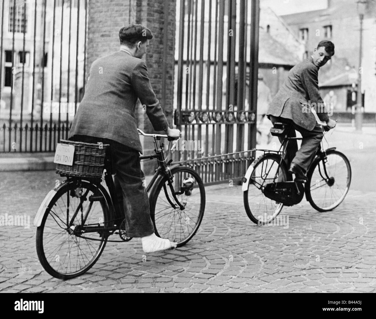 Fahrräder Bikes Fahrräder kann 1949 ein Cambridge Student mit seinem Fuß in Badages und sitzen auf seinem Fahrrad von einem anderen abgeschleppt wird Stockfoto