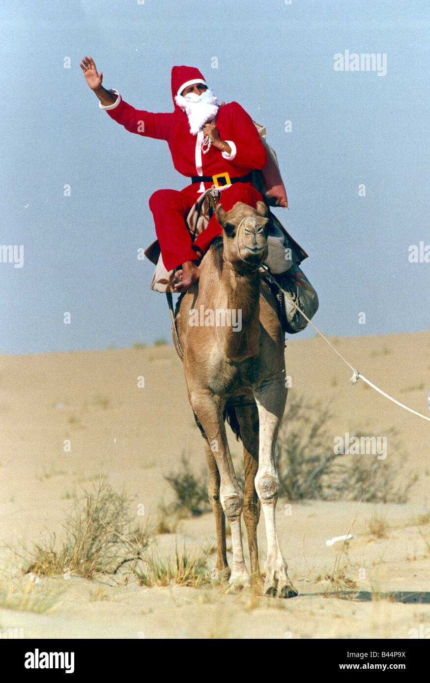 Santa Claus Wellen aus auf seinem Kamel in der Wüste auf dem Weg zum Übermitteln einer Nachricht an britische Truppen in der Golfregion Stockfoto