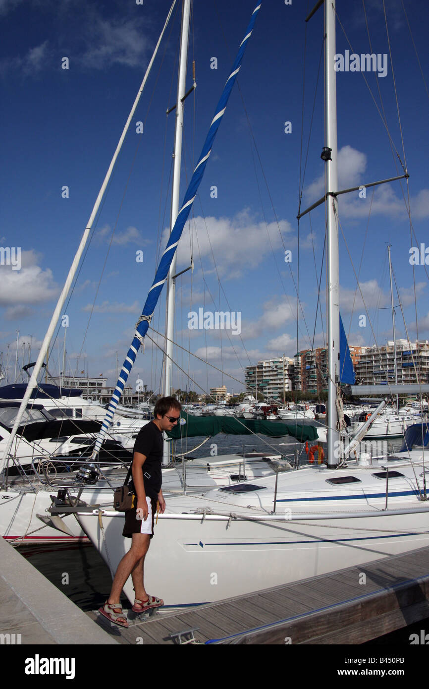 Junger Mann zu Fuß entlang einer Fußgängerbrücke in einem Liegeplatz Kai in Marina Miramar, Santa Pola Stockfoto