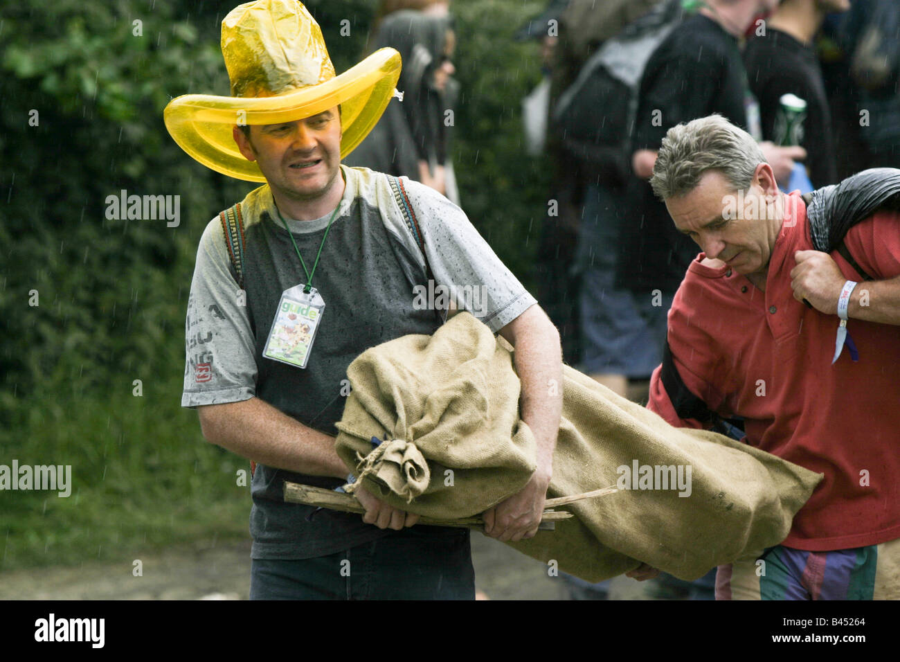 Neuzugang mit aufblasbaren Regenhut und Zelt als Regen zu fallen beginnt. Glastonbury Musikfestival Stockfoto