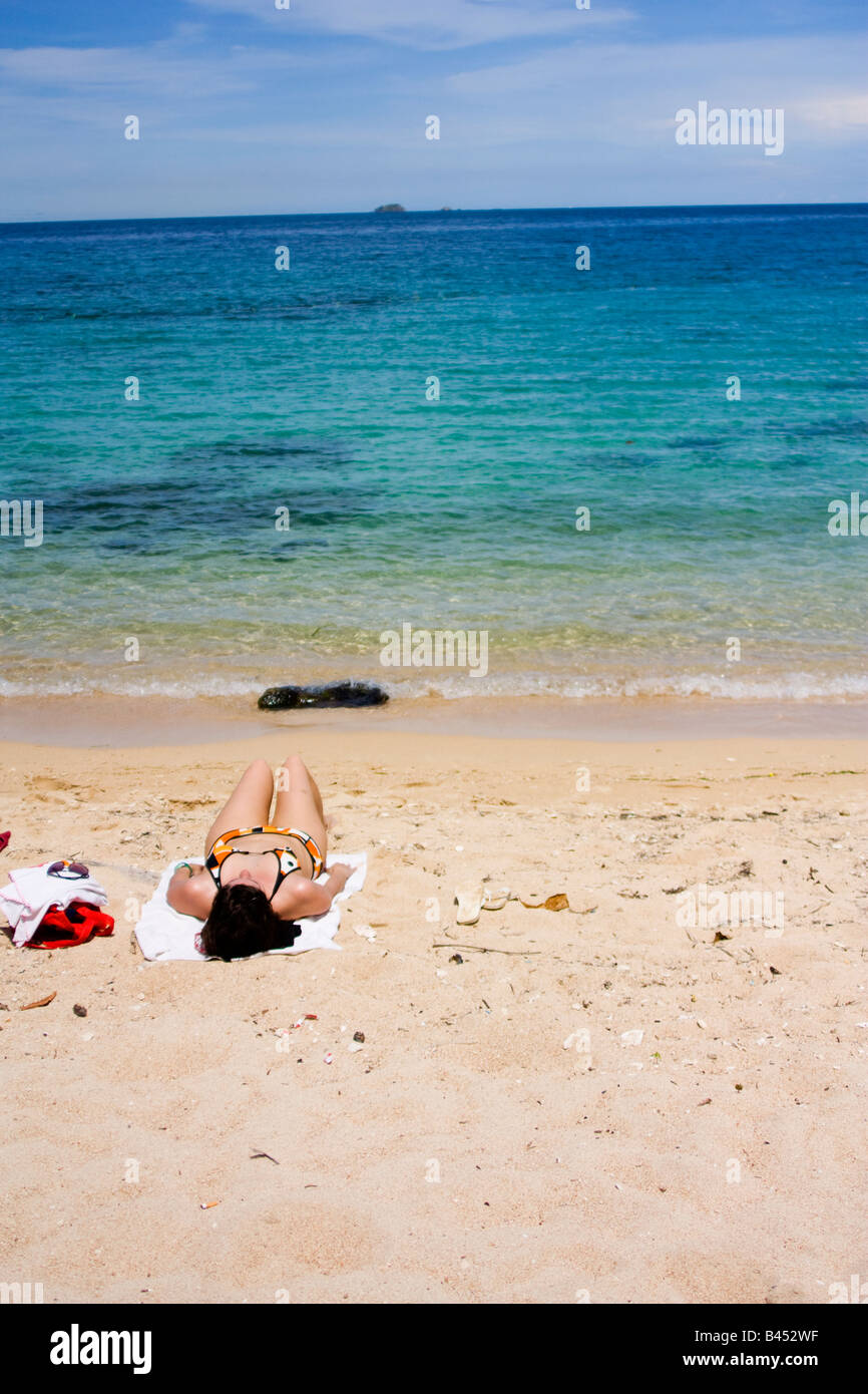 Panama, Isla Grande, Tourist bekommt eine Sonnenbräune liegend im Sand auf der panamaischen Karibik Stockfoto