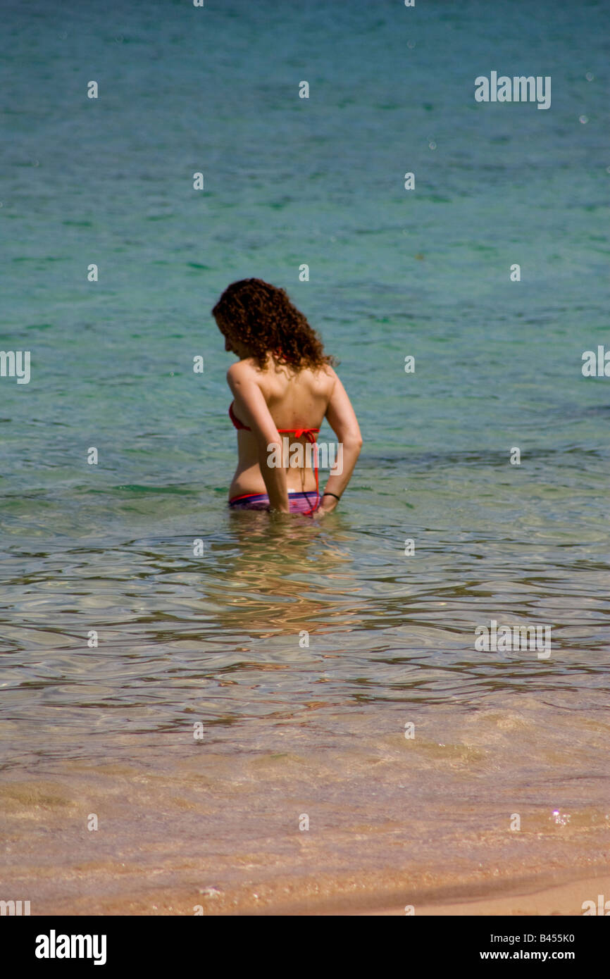 Panama, Isla Grande, junge Frau geht in die kristallklaren Wasser der Karibik, während sie ihrem Bikini behebt Stockfoto