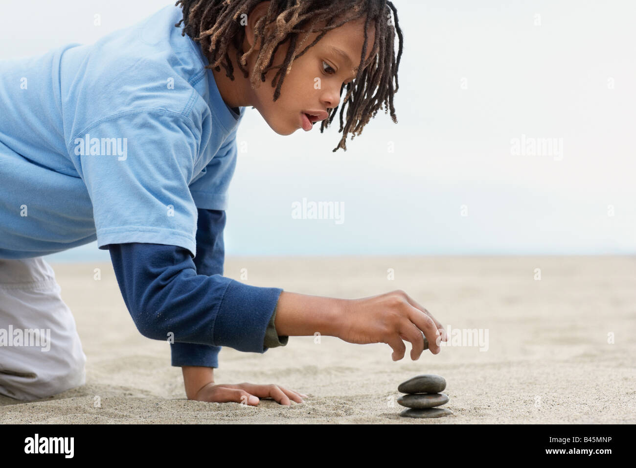 Gemischte Rennen junge Stapeln Steinen auf sand Stockfoto