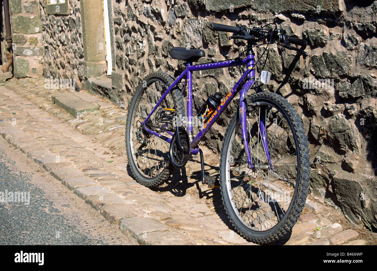 Hell lila Fahrrad Mountainbike, lieh gegen alte Steinmauer des Hauses  Cobbled Straße Mountainbike Stockfotografie - Alamy