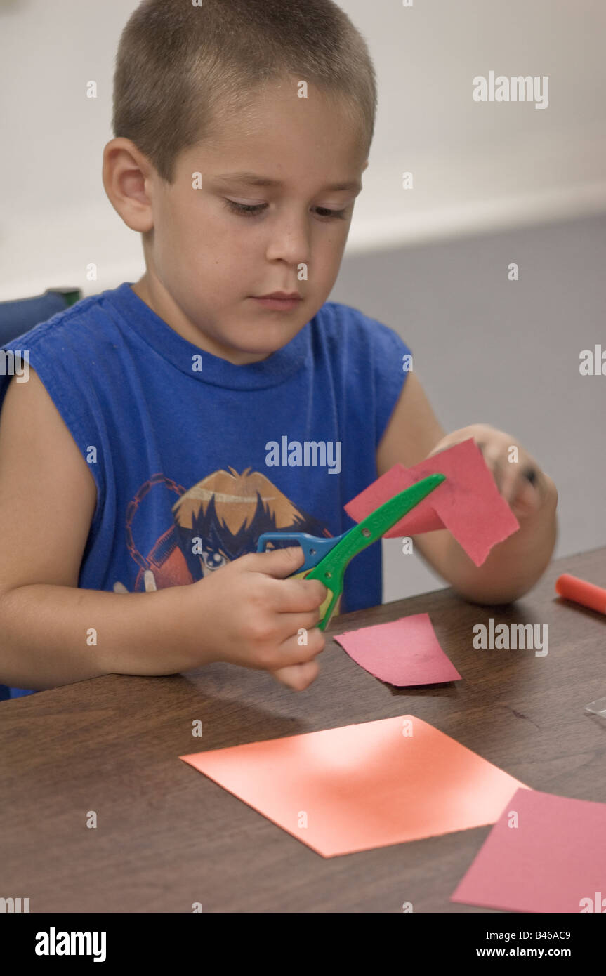 junge arbeitet auf Craft-Projekt mit einer Schere schneiden von Papier Stockfoto