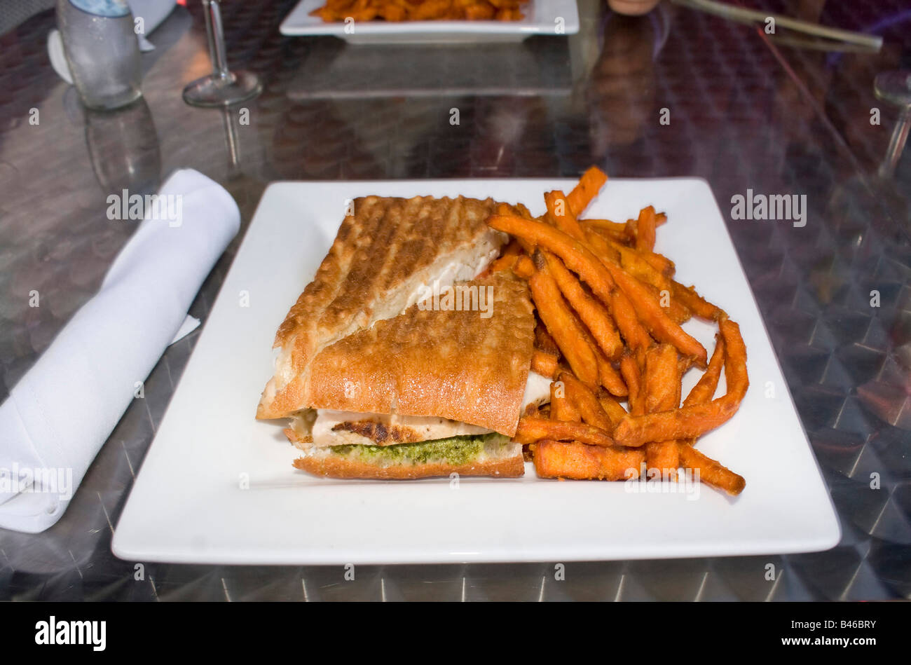 Eine leckere Hähnchen Pesto und Tomate Panini Sandwich mit einer Seitenlänge von Süßkartoffel Pommes frites Stockfoto