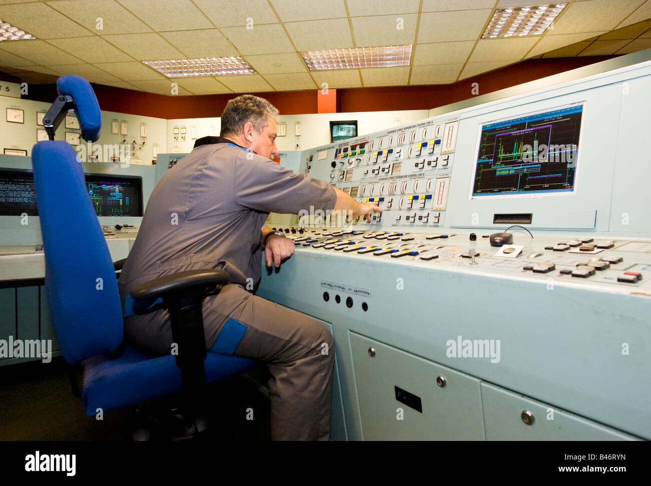 Ingenieur im Overall betreibt eine große komplexe Konsole in den hi Tech Kontrollraum ein UK-Kraftwerk Stockfoto