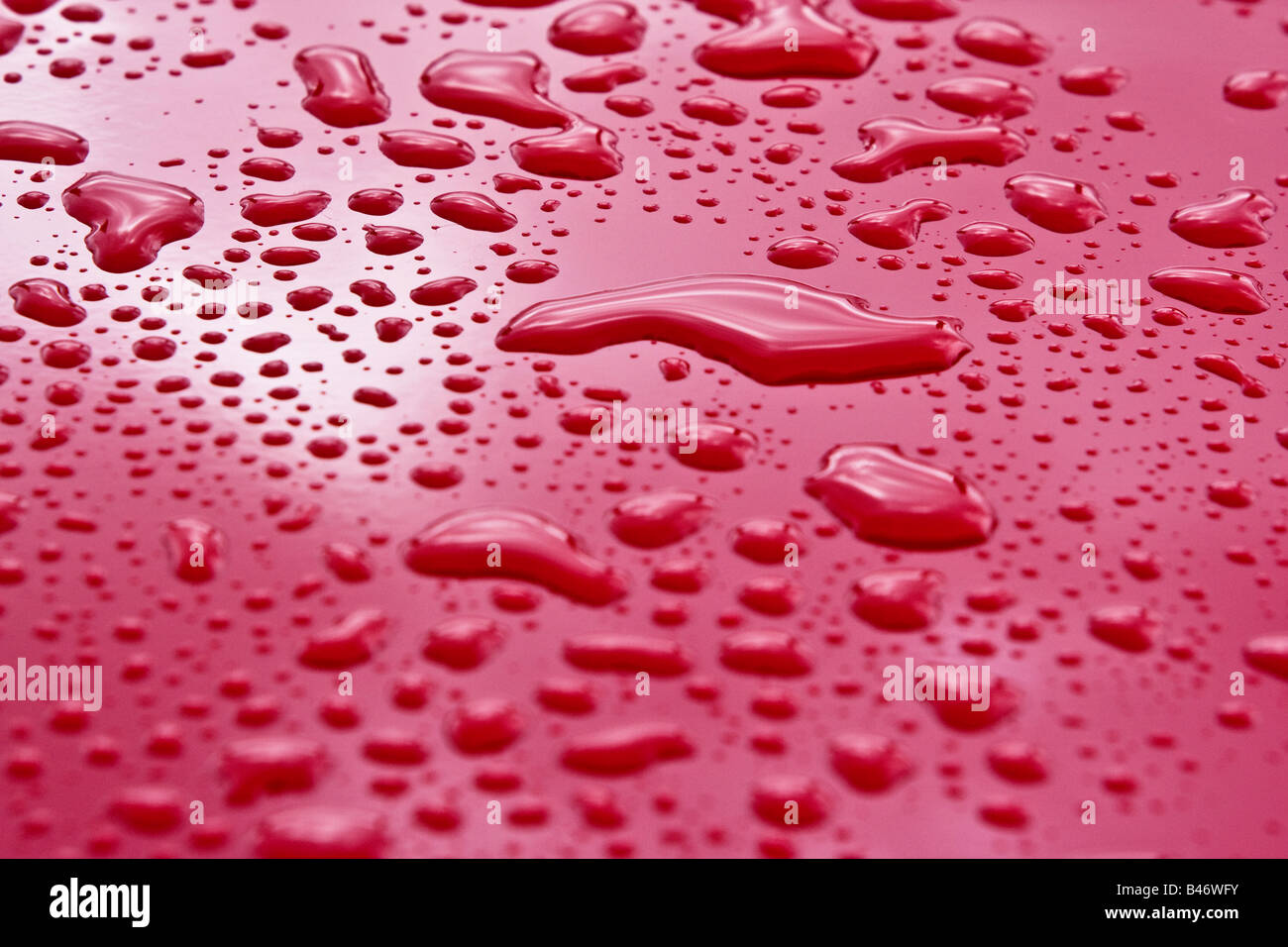 Flüssigkeit tropft auf rote Fläche Stockfoto