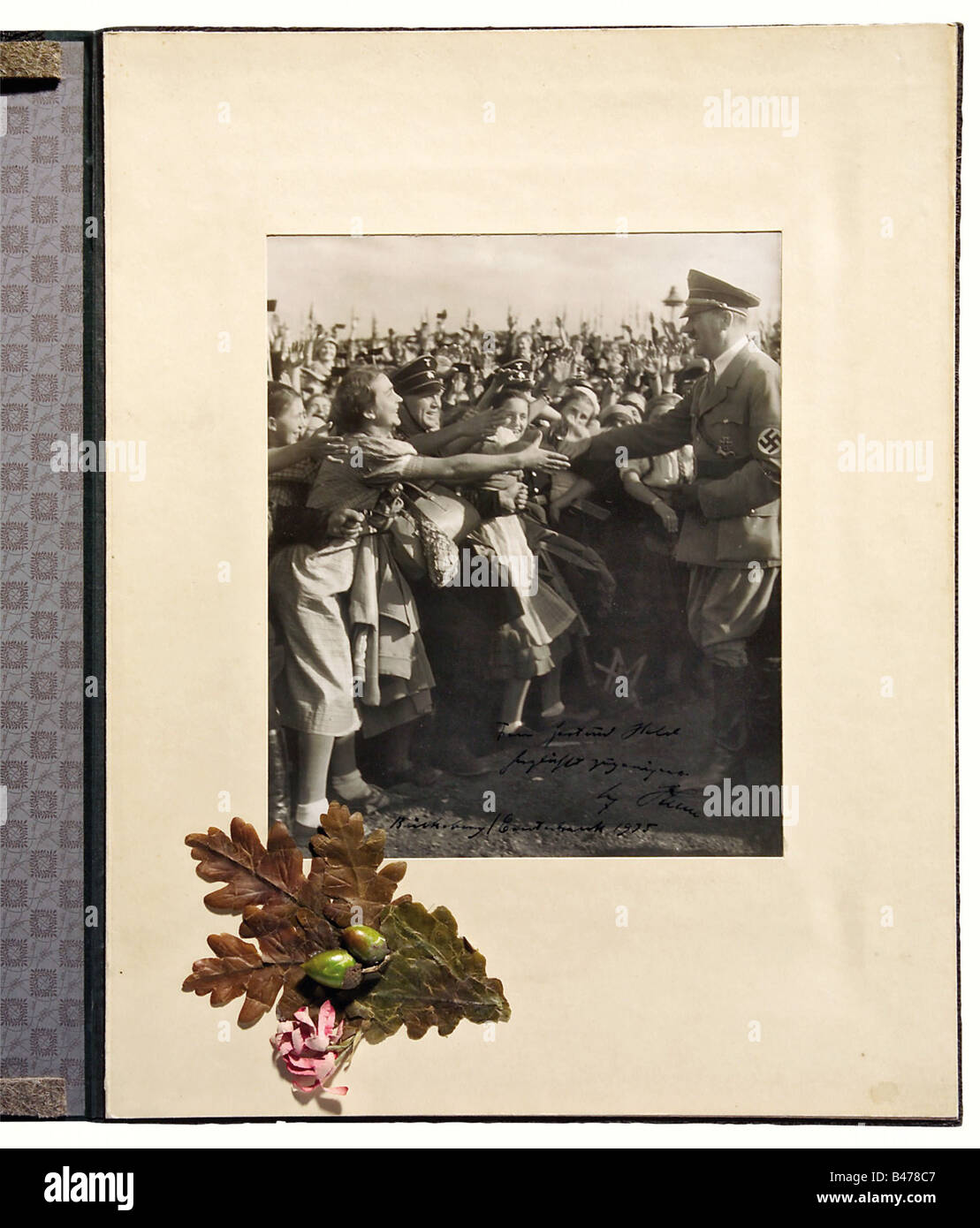 Gertrud Hielt - Adolf Hitler., EIN großes Foto mit einer Autogramm-Widmung in schwarzer Tinte, "Frau Gertrud Hielt herzlichstes Zugeeignet - Adolf Hitler - Bückeburg, Erntedank 1935". (Frau Gertrud Hielt Liebevoll fest - Adolf Hitler - Bückeburg, Erntedankfest 1935). In einem Passepartout mit Pasten auf dem Eichenblatt. Fotogröße 26 x 21 cm. In einer Mappe, mit zwei handgemalten Porträts von Bauernfrauen. Gertrud Held war die Ehefrau des örtlichen Bauernführers Günther Held in der nationalen Bauernorganisation. Menschen, 1930er, 20. Jahrhundert, Foto, Foto, Fotogr, Stockfoto