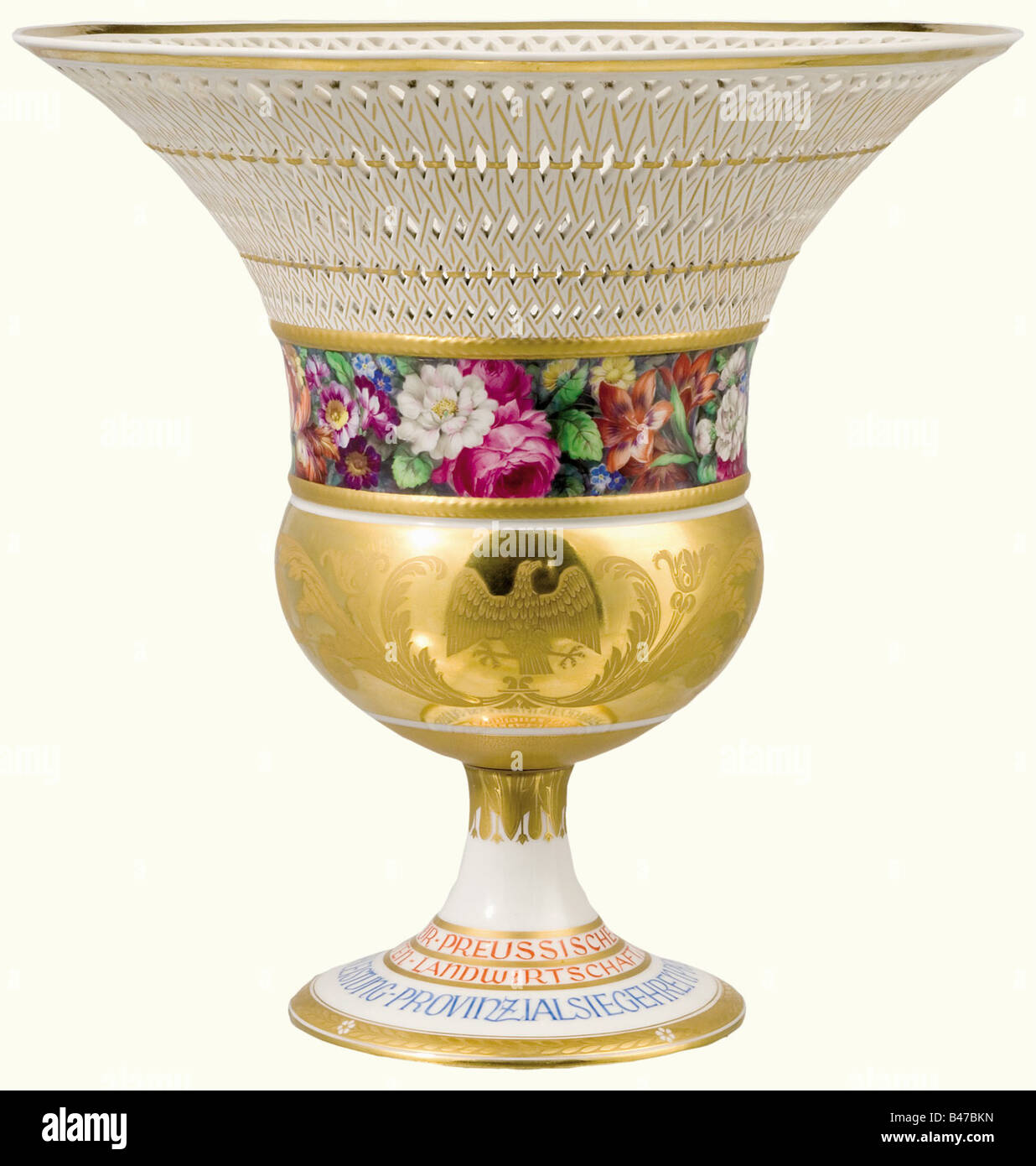 Eine KPM-Vase- und Prämienzertifikation (Königliche Porzellanmanufaktur) - der erste Preis der Provinz Prußisch 1932., Die Vase nach einem Schinkel-Entwurf, der sogenannte 'Schinkel Basket'. Weißes Porzellan. Der Kelch mit einem preussischen Adler und Blumenschmuck, der in Gold mit farbigen Blumen darunter geätzt ist. Die weit ausgebaute Felge in einem offenen Arbeitskorbmuster. Der Sockel ist aufgeschraubt und trägt die umlaufende Aufschrift "Preussisches Ministerium für Landwirtschaft, Domänen und Forsten - Provinzsiegerpreis für höhere Milchwirtschaft" (Preußenes Ministerium für Landwirtschaft, Weide, Stockfoto