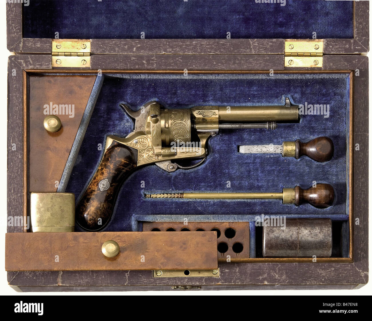 Ein gekämmter bronzener Flimmerschrevolver, Liege, um 1865. Kaliber 7,5 mm Lefaucheux. Keine Nummer. Fass und Rahmen aus Bronze. Rundzylinder, Sechs-Schuss-Zylinder. Klapptrigger. Zylinder, Rahmen und Fassboden weisen fein gravierte Rocailleornamentik auf. Die Griffplatten bestehen aus Thuja-Wurzelholz. Die Eisenstücke sind leicht eingepfifft. Länge 18 cm. In einem Holzkoffer mit blauem samt und Accessoires. Das Äußere ist mit einem Festzelt verziert. Die Ecken sind hell. Schlüssel fehlt. Abmessungen 29 x 19 x 8,5 cm. Erwerbsscheipflichtig. Histori, Stockfoto