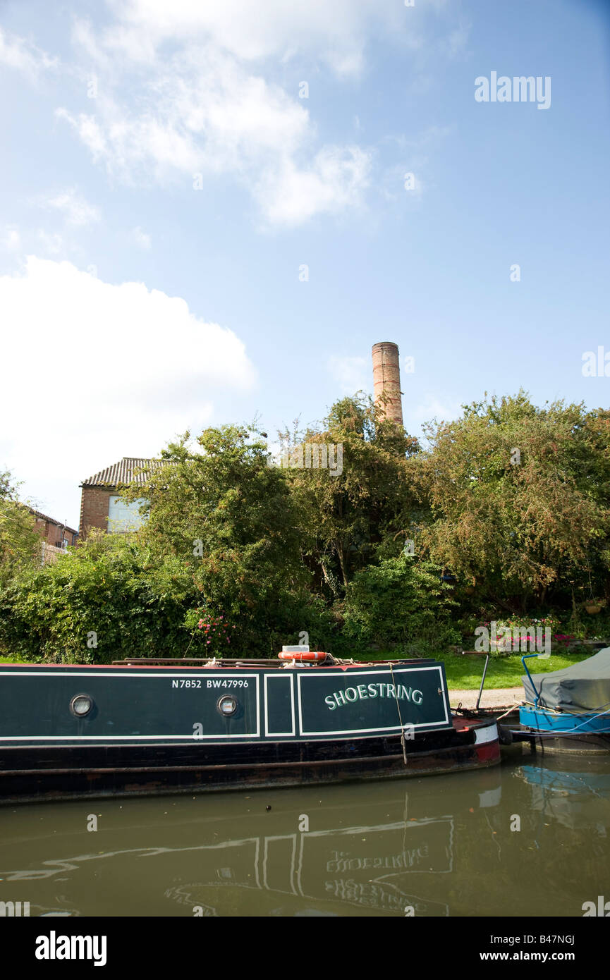 Eine alte Fabrikschornstein zu sehen in der Ferne hinter einem Boot auf dem Grand Union Canal in West London Stockfoto