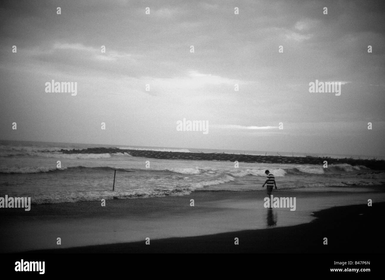 Mann allein zu Fuß am Strand an einem bewölkten Tag. Stockfoto