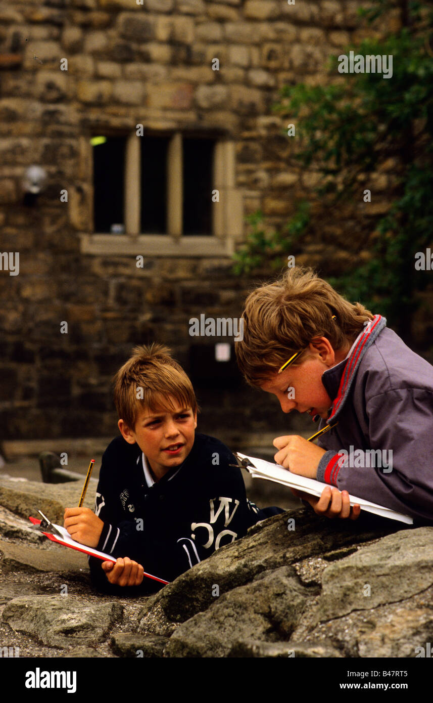 Zwei Jungs machen Zeichnungen af architektonische Details bei einem Schulbesuch in eine historische Stätte. Stockfoto