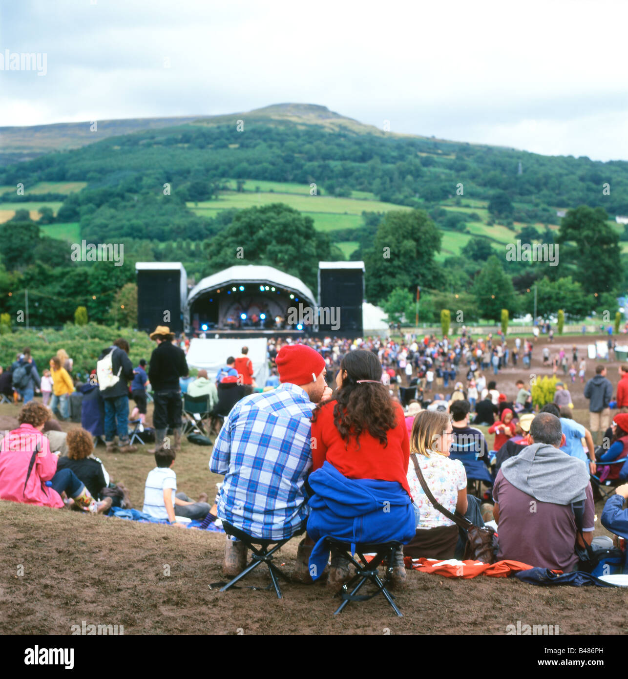 Leute sitzen auf dem schlammigen Hügel beobachten die Bühne auf der Green-Mann-Festival am Glanusk in der Nähe von Abergavenny Wales UK KATHY DEWITT Stockfoto