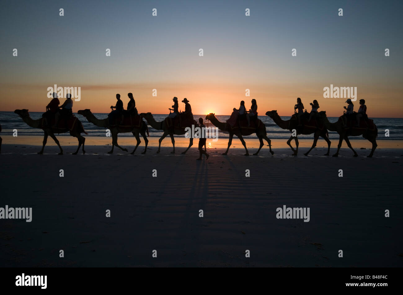 Kamel Züge tragende Touristen bei Sonnenuntergang am Cable Beach in der Nähe von Broome Western Australia Stockfoto