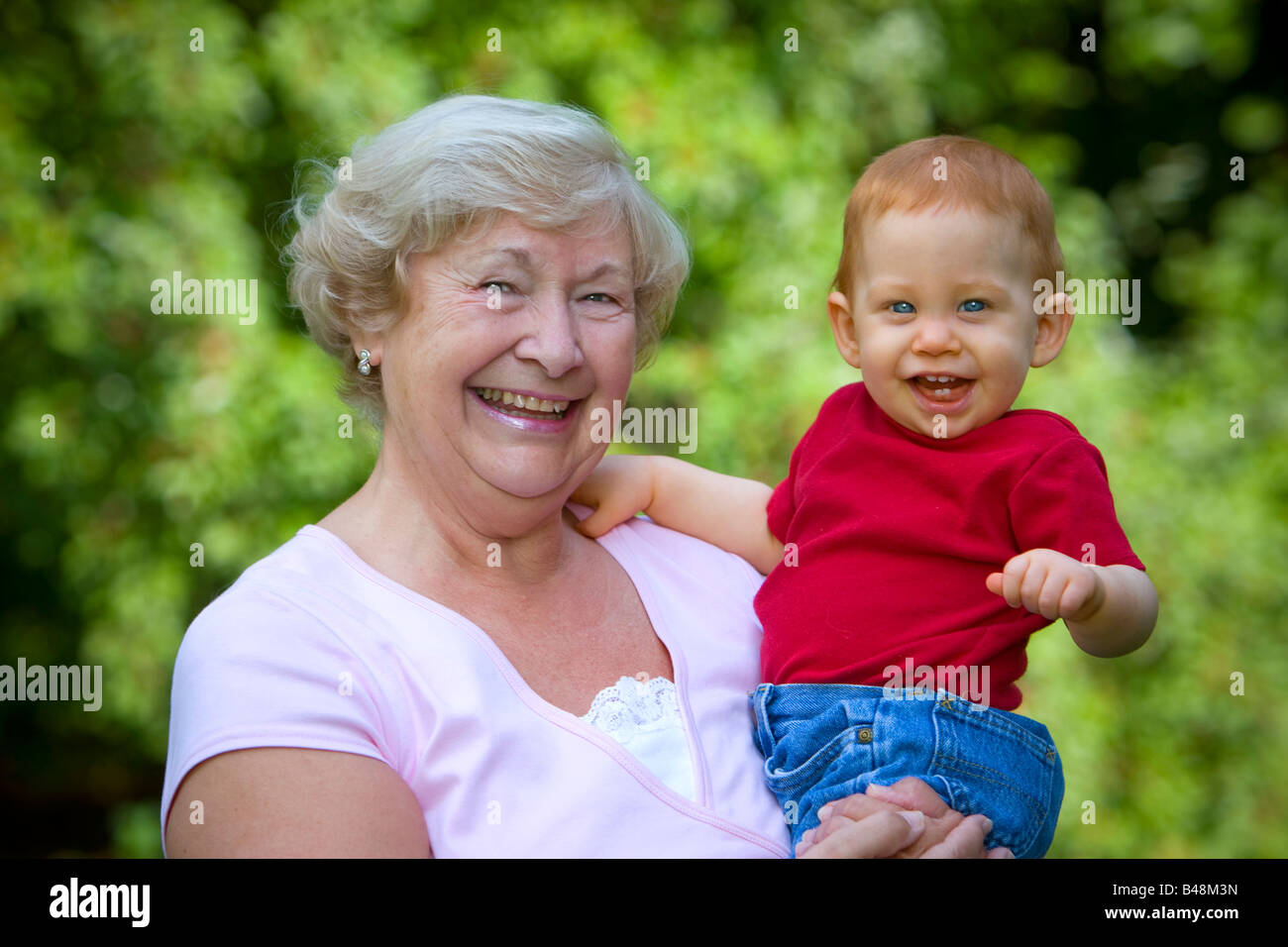 Großmutter Holding glücklich Enkel im sonnigen Garten Stockfoto
