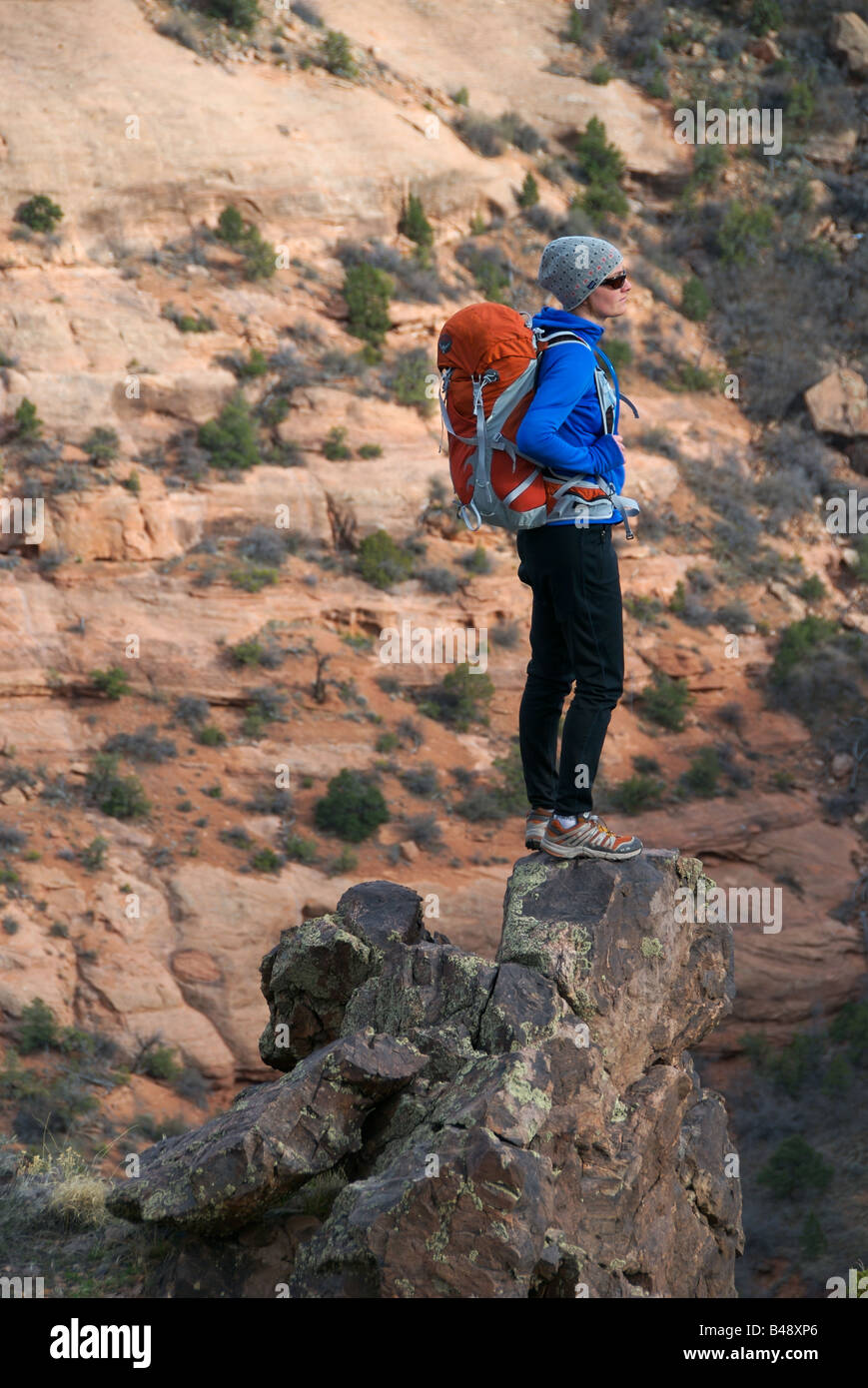 ein Frauen-Anstiege auf steilen Sandsteinfelsen mit einer Packung in der Colorado-Wüste Stockfoto