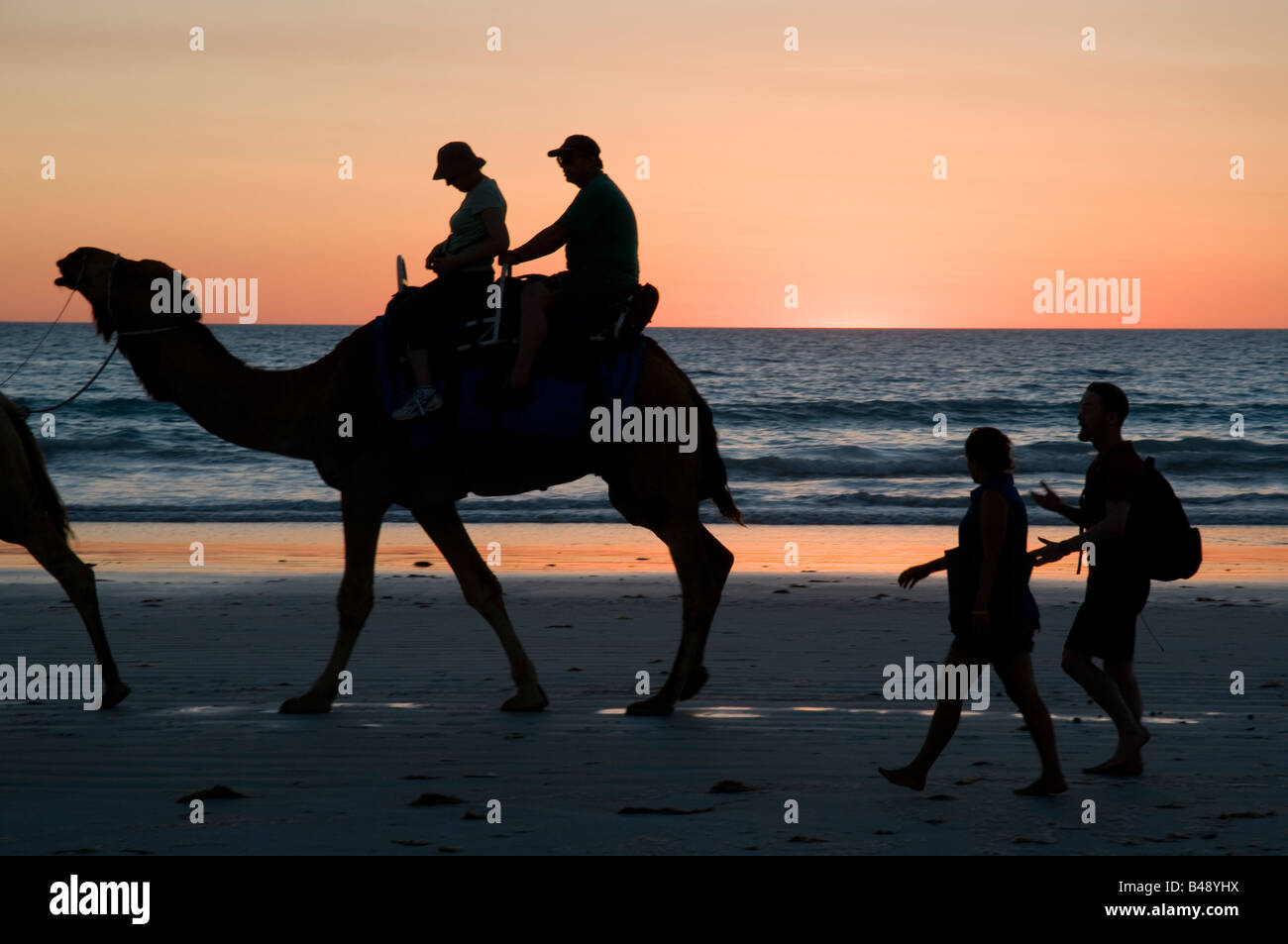 Kamel Züge tragende Touristen bei Sonnenuntergang am Cable Beach in der Nähe von Broome Western Australia Stockfoto