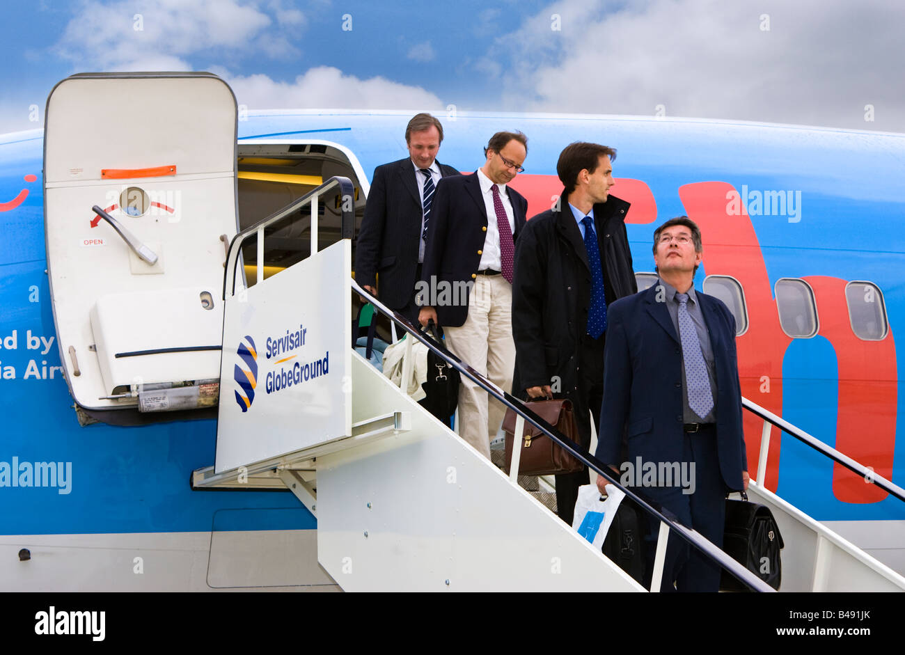 Vier Unternehmer Passagiere 737 Flugzeug verlassen und zu Fuß Schritte UK Stockfoto