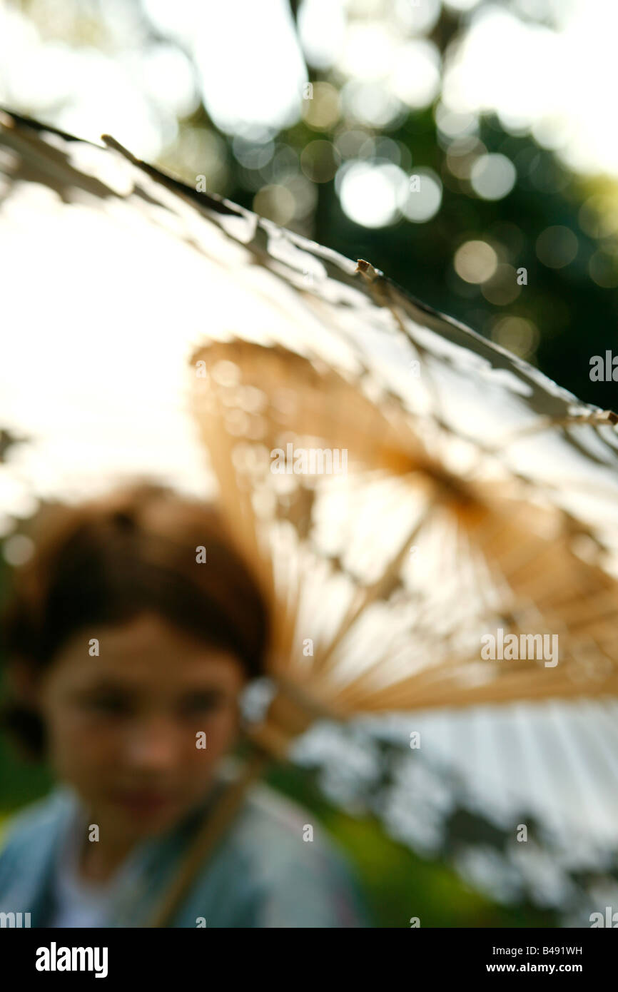 Ein junges Mädchen hält einen chinesischen Pergament-Schirm während eines Nachmittags Gartenparty. Stockfoto