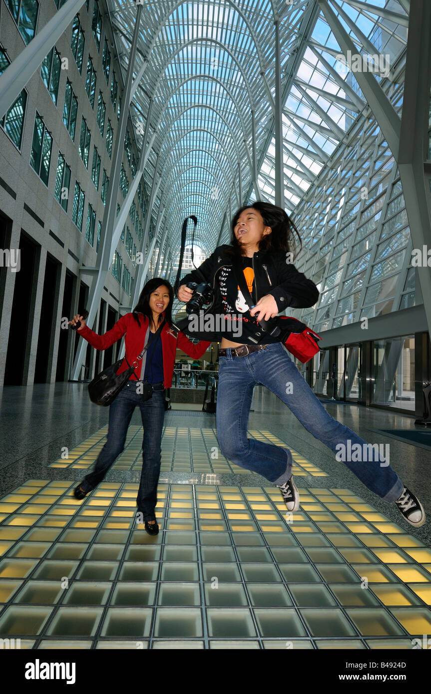 Zwei orientalische weibliche Touristen springen vor Freude im BCE Place Allen Lambert Galleria Atrium in Toronto Kanada Stockfoto