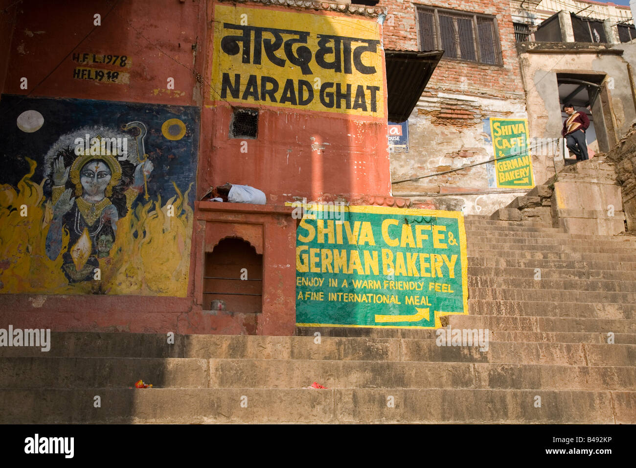 Schritte bei der Narad Ghat in der Stadt von Varanasi, Indien. Werbung und ein religiöses Bild gemalt an den Wänden zu sehen. Stockfoto