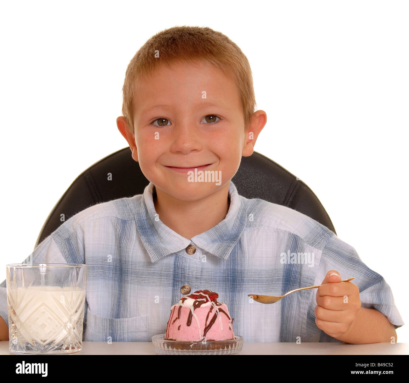 Kleiner Junge sitzen und Essen eine Dessert an einem Tisch Stockfoto