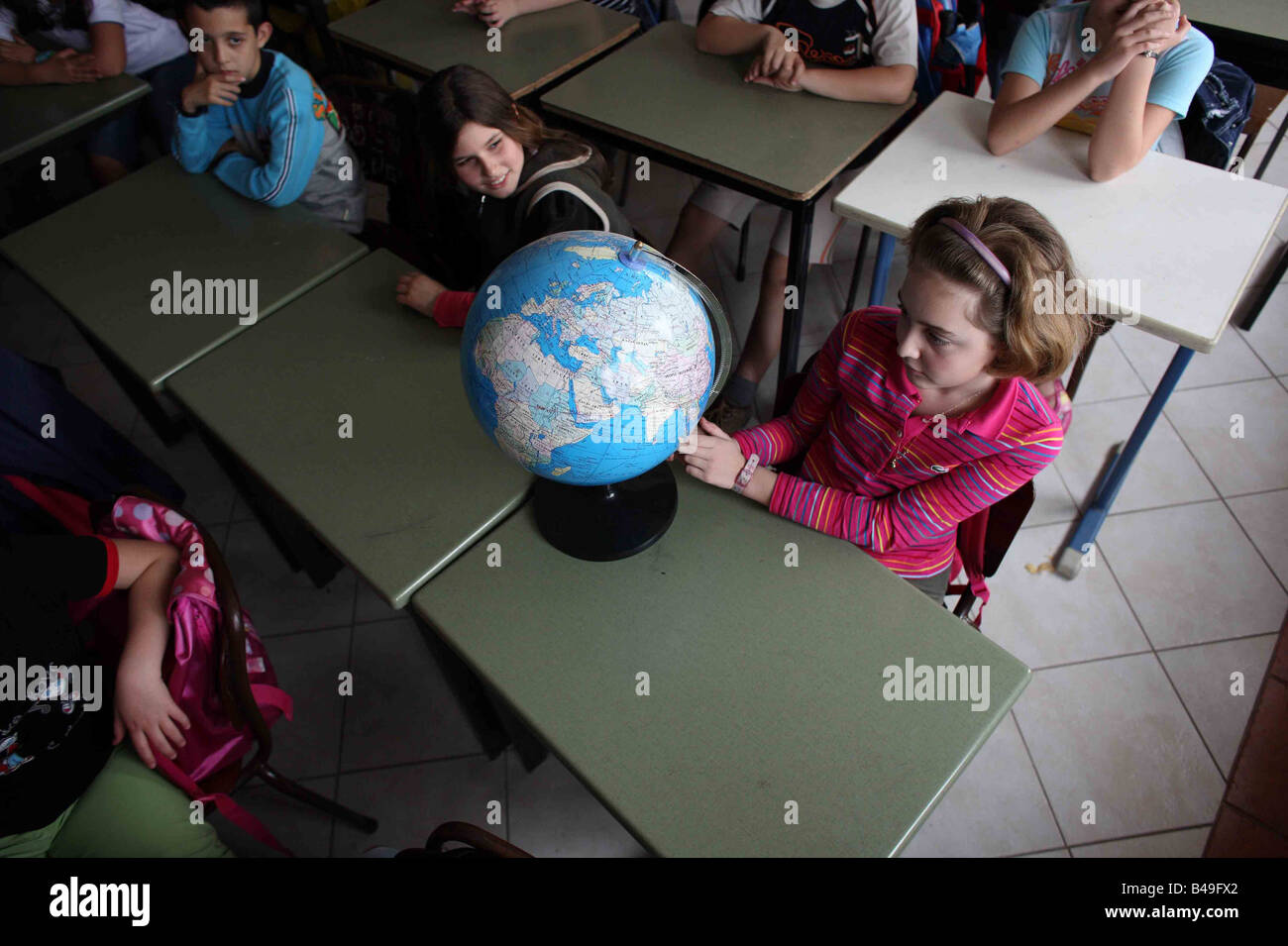 Junge Mädchen auf der Suche im Globe im Klassenzimmer in der Schule in Tirana, Albanien Stockfoto