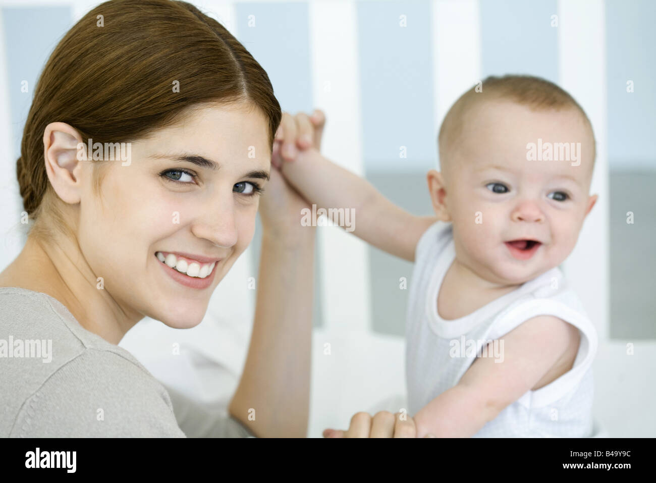 Mutter des Babys Händchen und lächelt in die Kamera Stockfoto