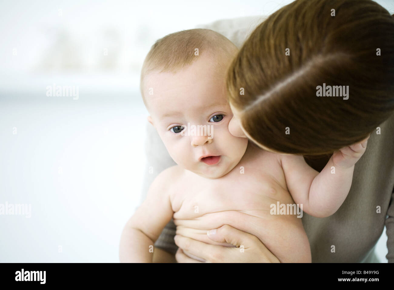 Frau küsst die Wange des Babys, Baby Blick in die Kamera Stockfoto