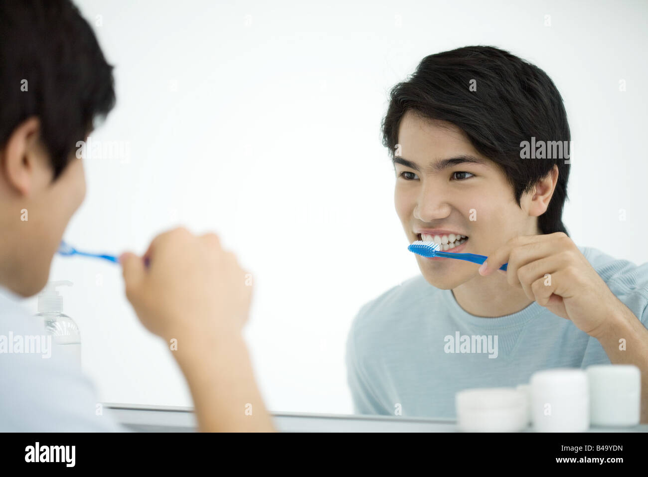 Junger Mann, Zähne putzen, selbst im Spiegel betrachten Stockfotografie -  Alamy