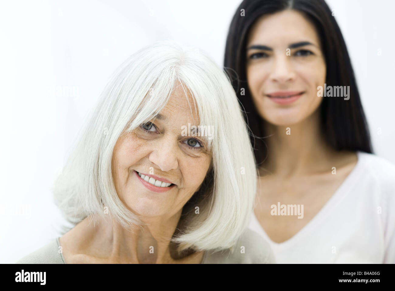 Ältere Mutter und Erwachsene Tochter lächelnd in die Kamera, konzentrieren sich auf Vordergrund Stockfoto