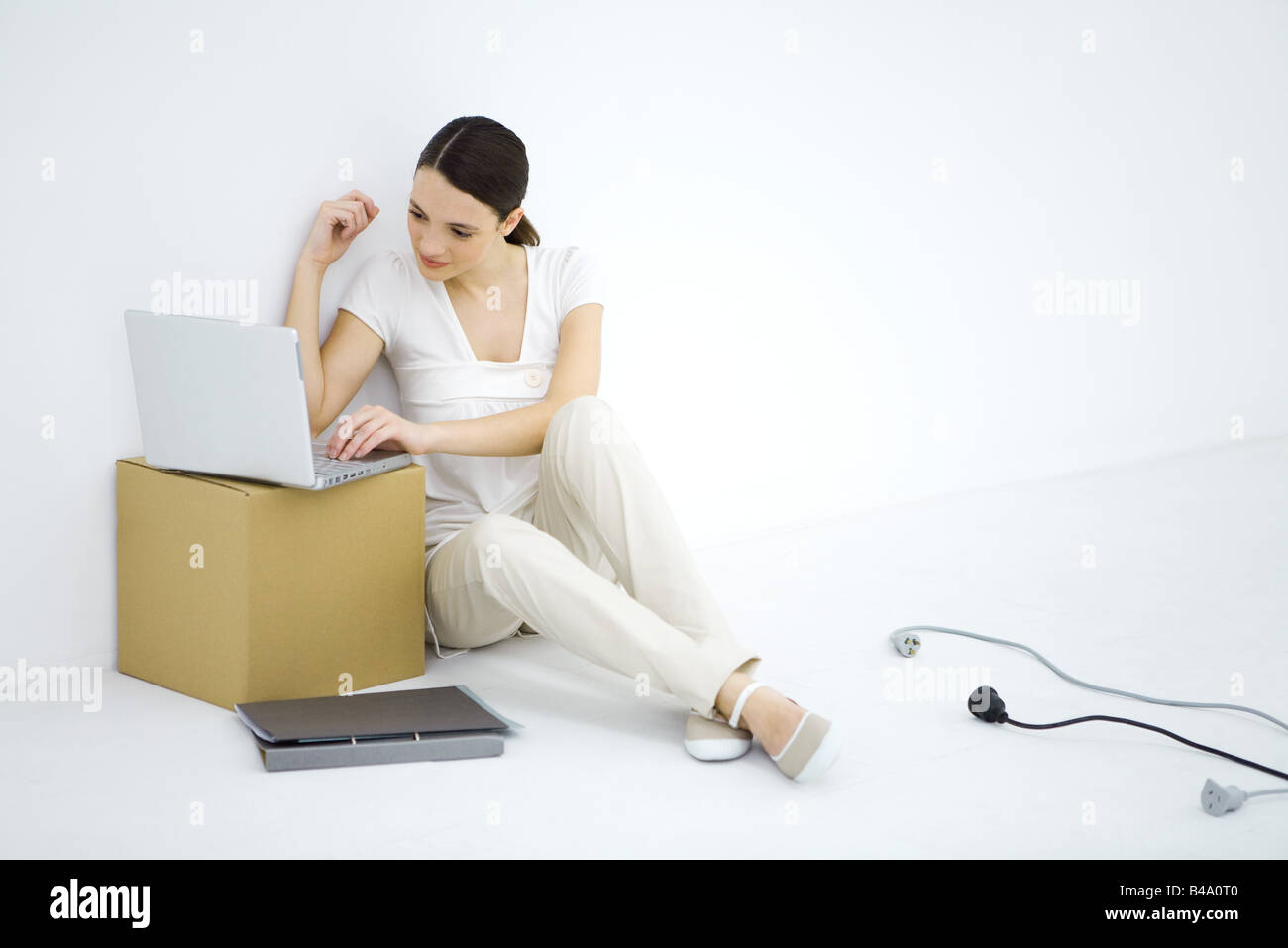 Frau sitzt am Boden, mit Laptop-Computer setzen auf Karton Stockfoto