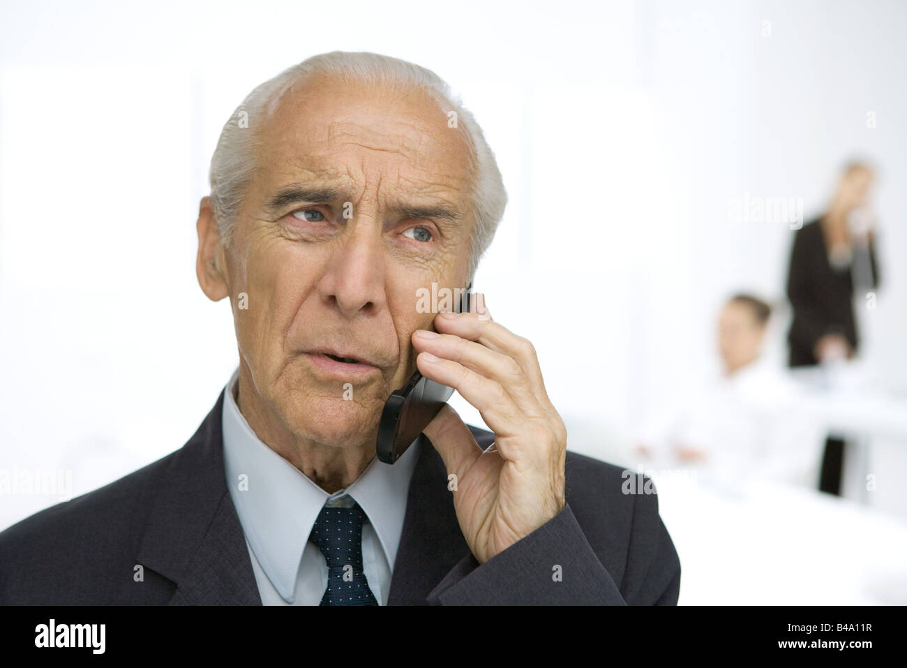 Leitenden Geschäftsmann mit Handy, gerunzelter Stirn Stockfoto