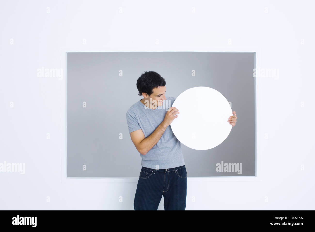 Mann sucht leere kreisförmige Zeichen in Händen, Lächeln Stockfoto