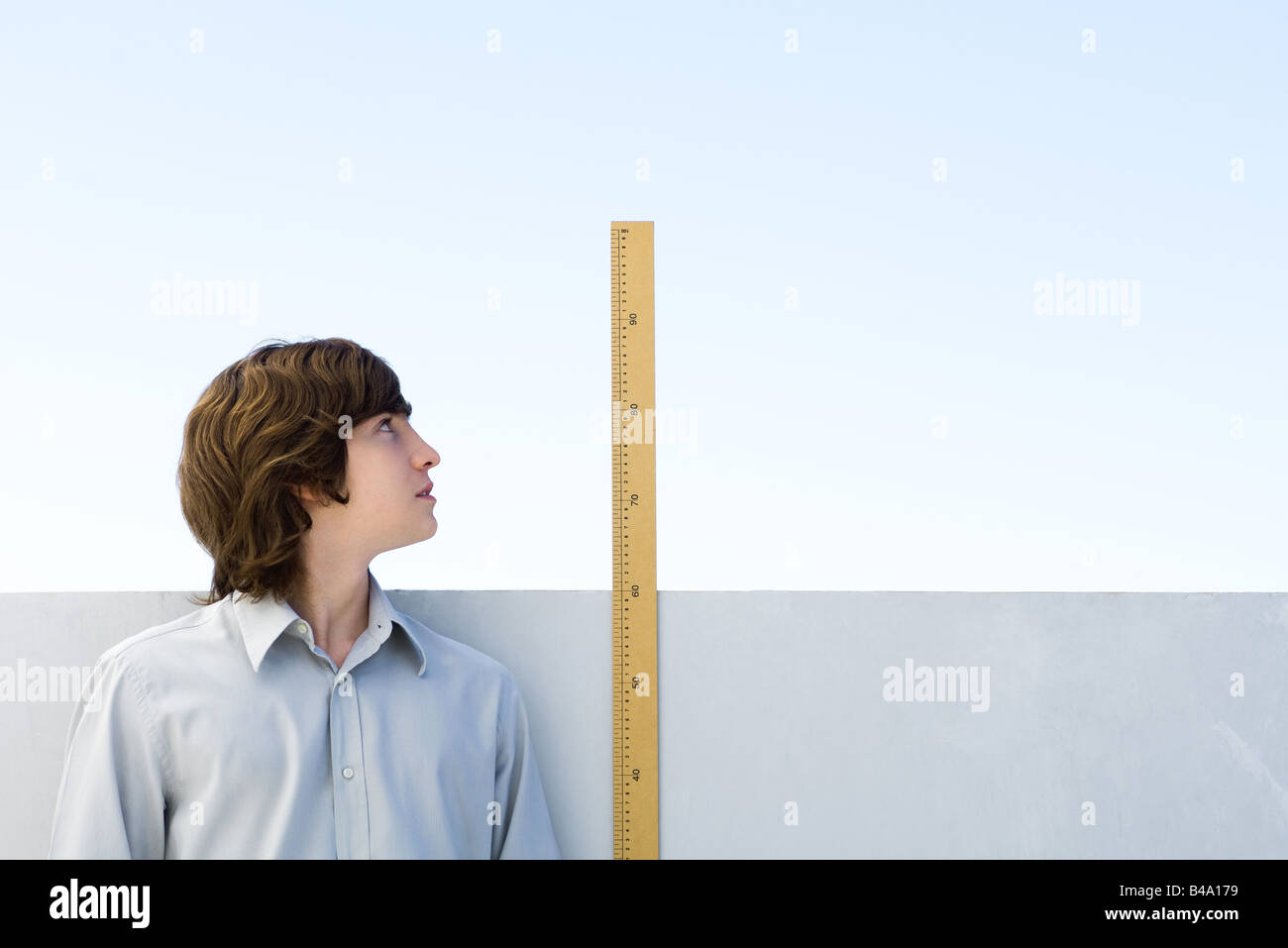 Junger Mann seine Höhe mit Lineal messen Stockfoto