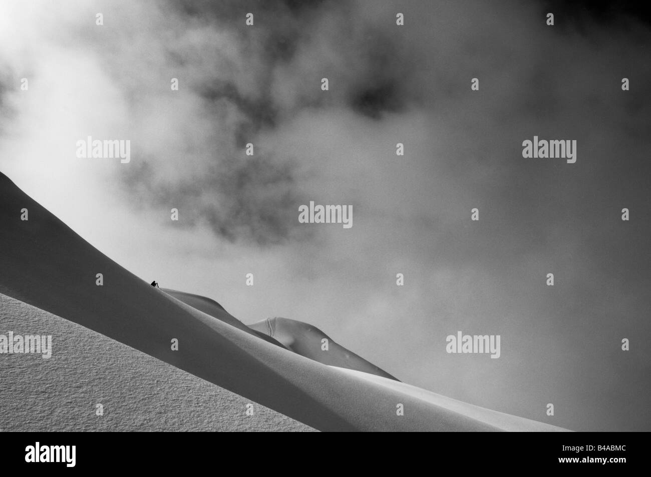 Ein einsamer Skifahrer in der Distnace Stadnign am oberen Rand eine unverspurten Hang Stockfoto